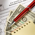 1040NR-EZ form with pen, notepad, and dollars