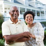 Picture of mature African American couple (50s and 60s) at a country club, standing in front of clubhouse. Main focus on woman.