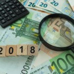 Foreign currency, 2018 in wooden blocks, and a calculator in the background.
