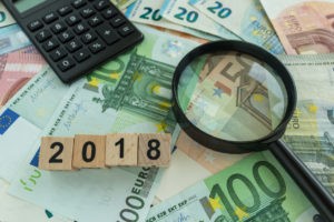 Foreign currency, 2018 in wooden blocks, and a calculator in the background.