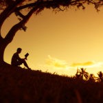 Picture of a man generating a business education deduction by reading a book under a tree