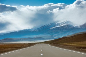 Picture for long run returns when saving for retirement blog post shows road in mountains area. of Siberia, Russia