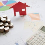 Real estate professional audit blog post image showing coins, a calculator, and a toy house.