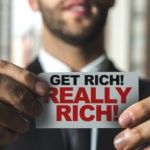Picture for spotting investment scams post, which shows a man holding a get really rich sticker