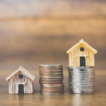 Picture of miniature houses stacked on coins for rate of return of everything blog post