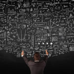 Picture of Young businessman standing in front of sketched charts and signs on a blackboard for the retirement savings Sec. 199A blog post