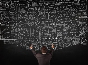 Picture of young businessman standing in front of blackboard trying to figure out how retirement savings change qualified business income deduction