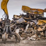 For partnership Section 199A blog post, a picture of Large tracked excavator working a steel pile at a metal recycle yard, France