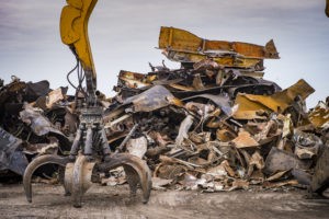 For partnership Section 199A blog post, a picture of Large tracked excavator working a steel pile at a metal recycle yard, France