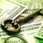 Picture of an old fashioned key on top of $100 dollar bills