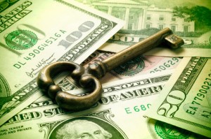 Picture of an old fashioned key on top of $100 dollar bills