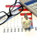 Picture of reading glasses, calculator and piggy bank on top of bar chart.