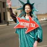 Picture of statute of liberty holding a sign that says income tax