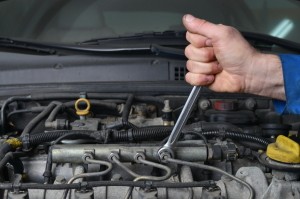 Man using a wrench in a car engine repair project.