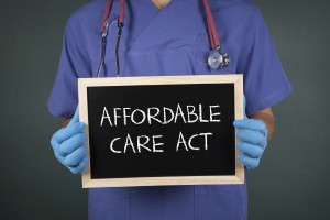 Picture of doctor holding blackboard with words "affordable care act."