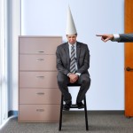 Business man wearing a dunce hat
