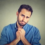 Closeup portrait of desperate young man showing clasped hands, pretty please with sugar on top isolated on gray wall background. Human emotion facial expression feelings, body language