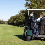 Picture of Golfing friends driving a golf car and going for a game of golf