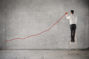 Picture of Businessman standing on a ladder and charting a graph with positive trend