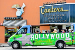 A picture of Los Angeles's Famous Canter's Deli Bakery and Restaurant, with a Hollywood sightseeing tour bus with tourists passing nearby.