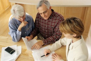 Picture of mature couple talking to financial planner at home.