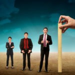 Hand holding wooden ruler, mesuring employee performance. Working appraisal concept