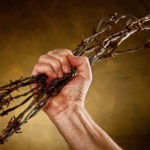 picture of man crushing a bundle of barbed wire